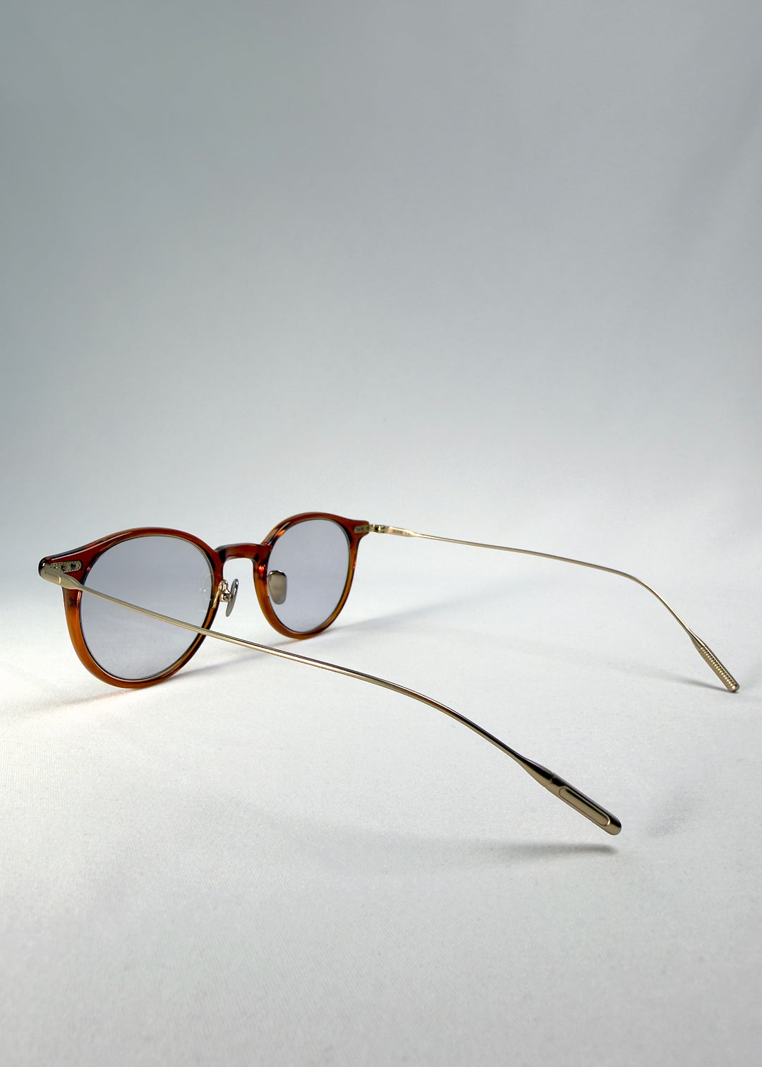 Back-angle view of Lunor Drift Softint sunglasses in Amber Mist displaying slender metal arms and warm amber frame details.