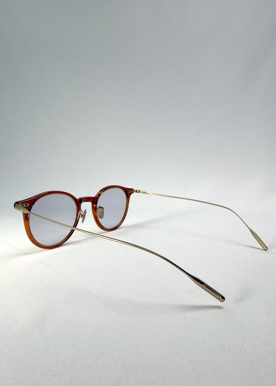 Back-angle view of Lunor Drift Softint sunglasses in Amber Mist displaying slender metal arms and warm amber frame details. 