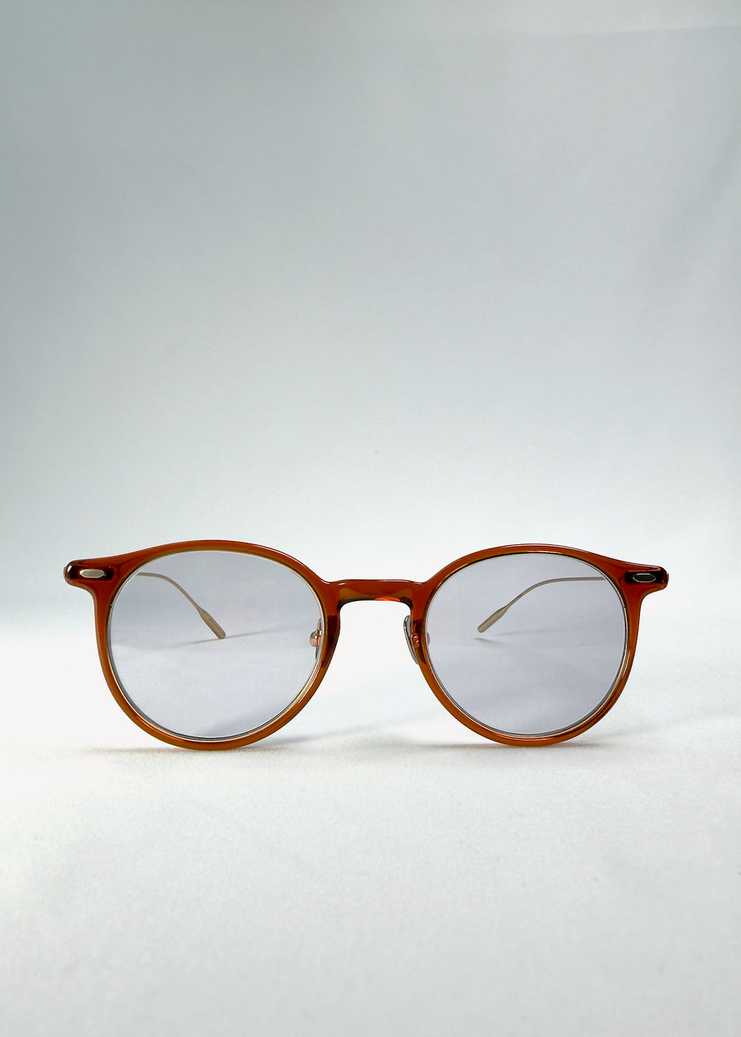 Front view of Lunor Drift Softint sunglasses in Amber Mist with warm amber round frame and softly tinted grey-brown Softint lenses.