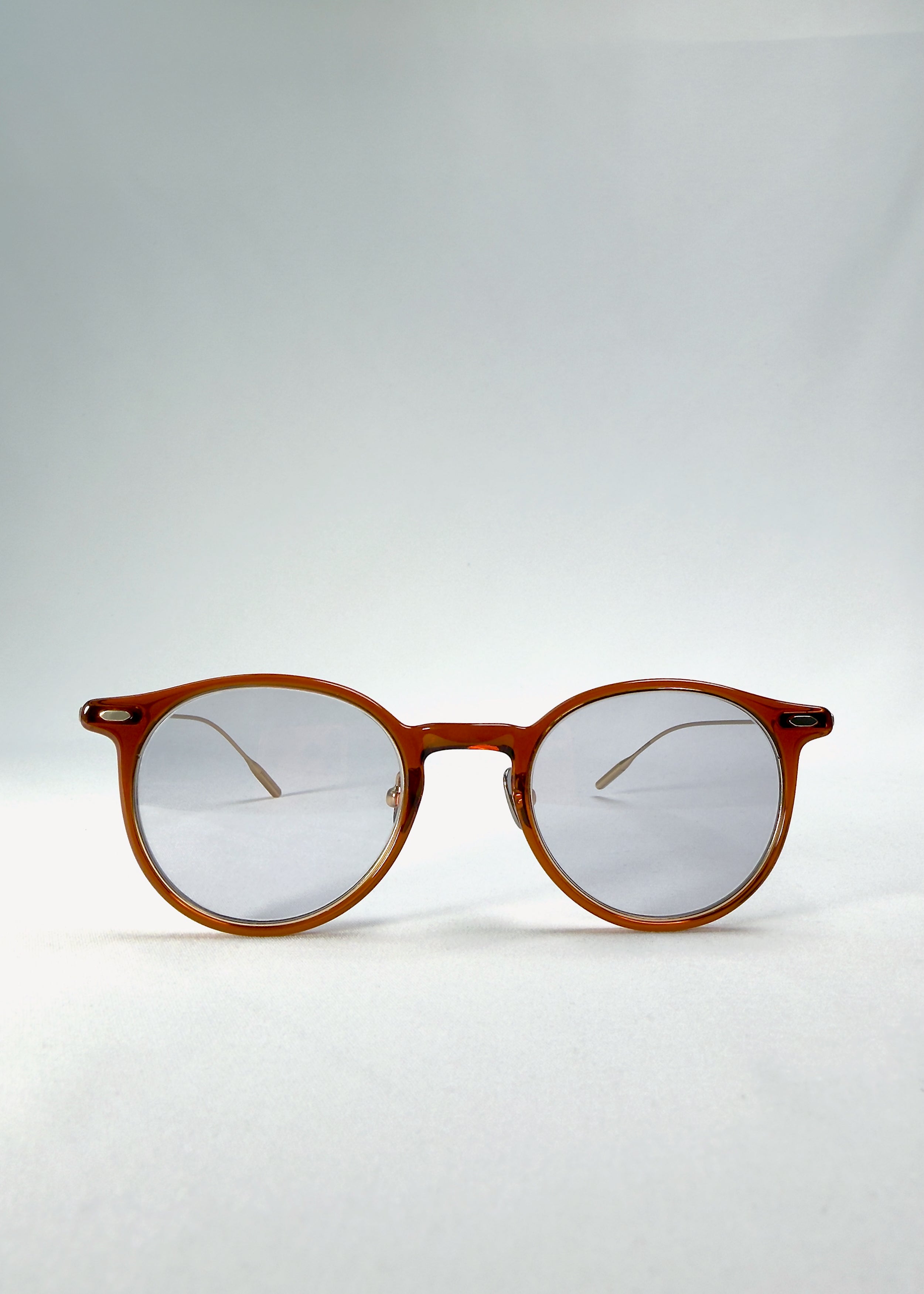 Front view of Lunor Drift Softint sunglasses in Amber Mist with warm amber round frame and softly tinted grey-brown Softint lenses.