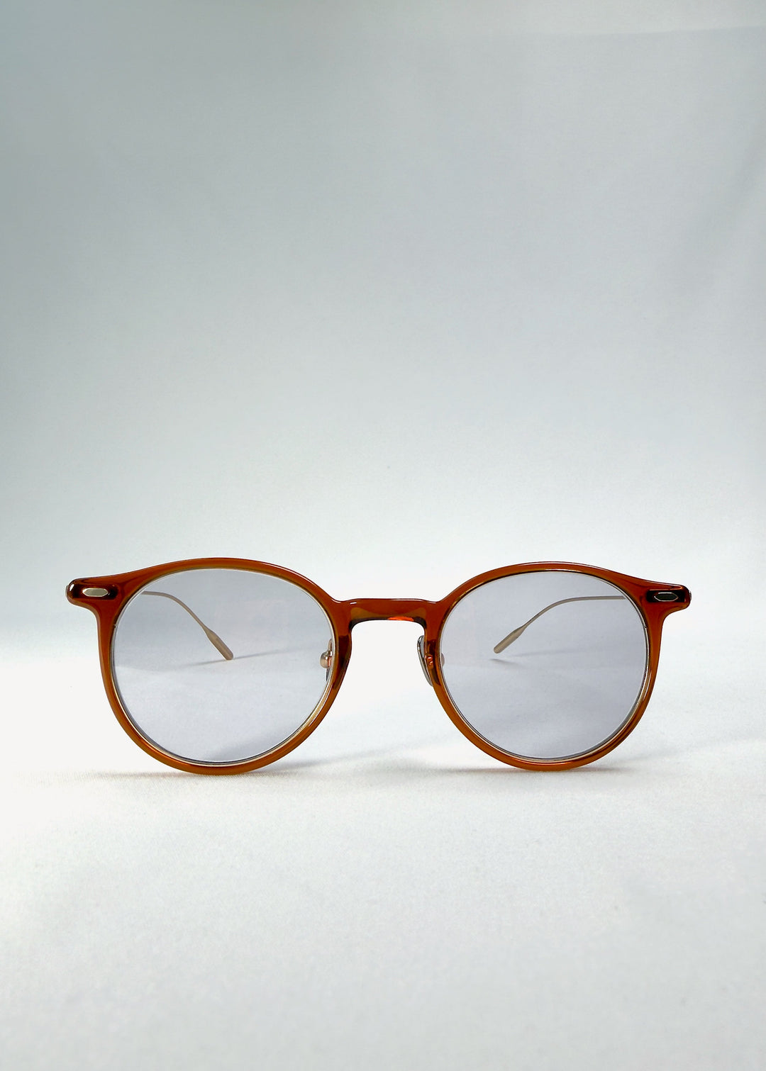 Front view of Lunor Drift Softint sunglasses in Amber Mist with warm amber round frame and softly tinted grey-brown Softint lenses. 