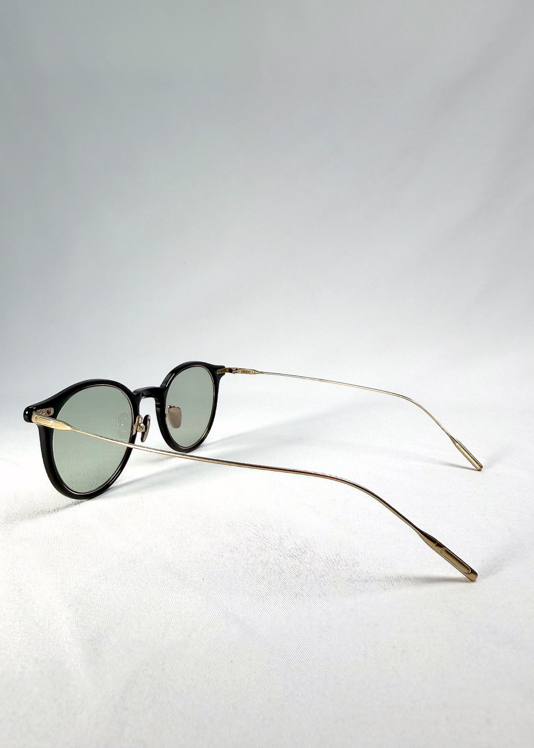 Back-angle view of Lunor Drift Softint sunglasses in Shadow Gleam showing translucent brown frame and gold titanium temples. 