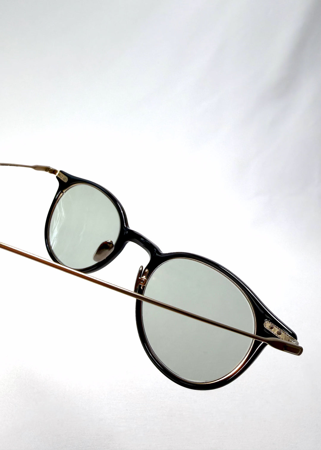 Close-up of Lunor Drift Softint sunglasses in Shadow Gleam showing gold titanium hinge detail and acetate frame texture. 