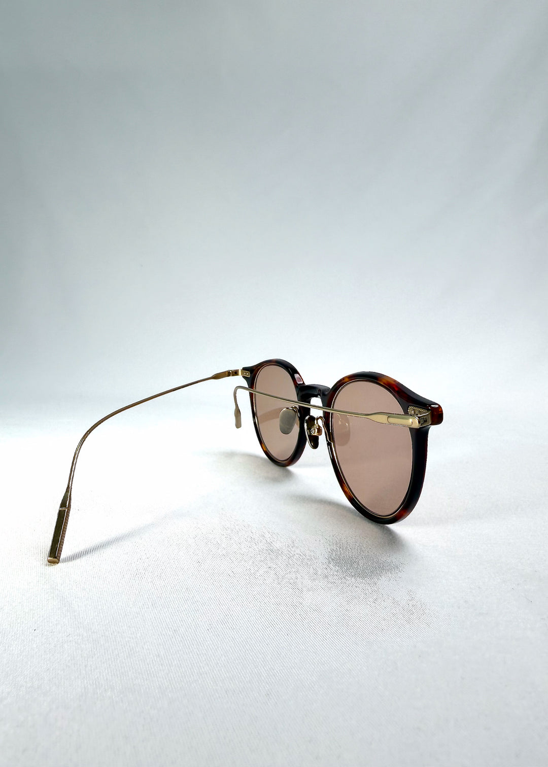 Folded-angle view of Lunor Drift Softint sunglasses in Umber Fade showing fine titanium arms and frame curvature.