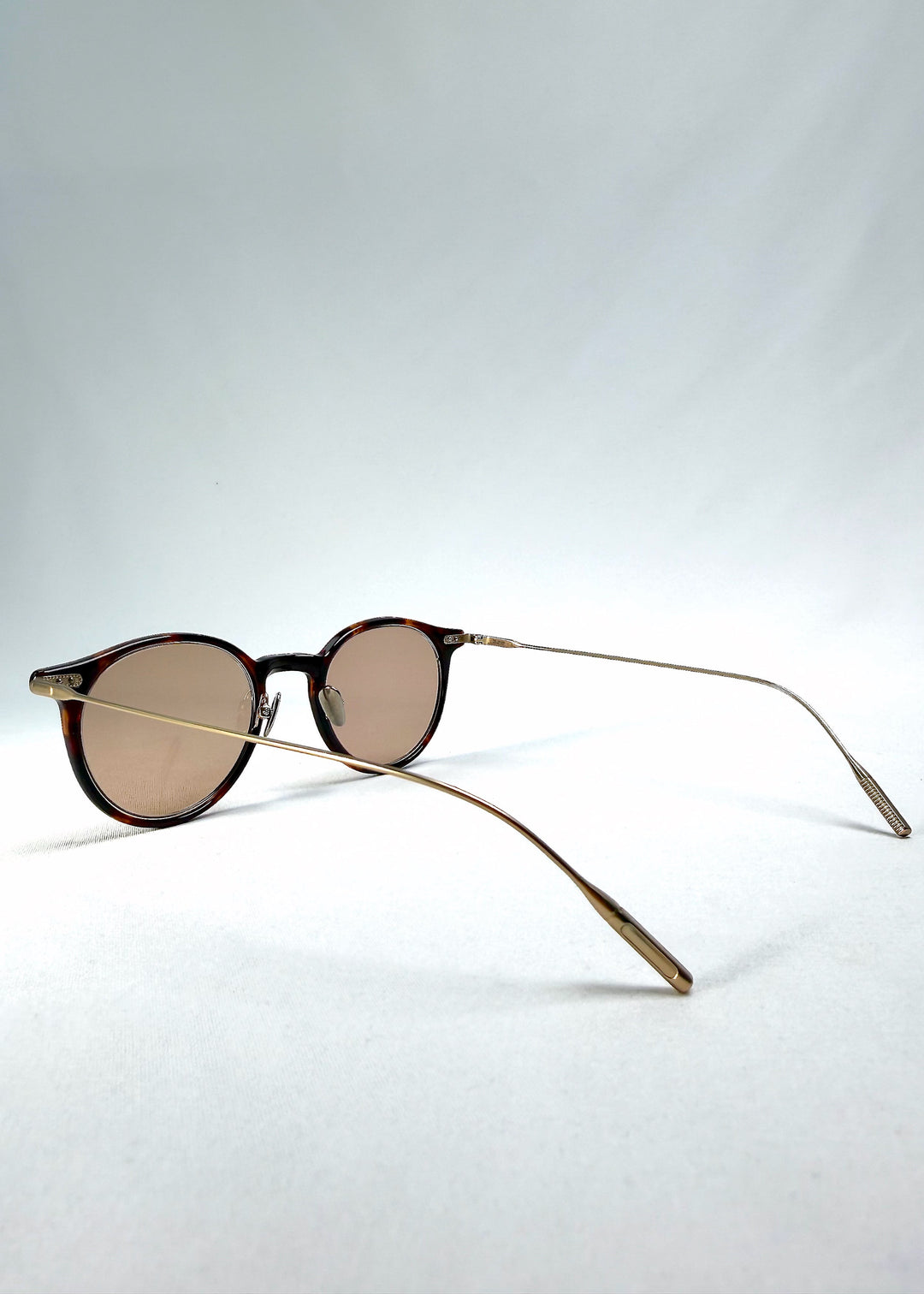 Side-temple view of Lunor Drift Softint sunglasses in Umber Fade showing curved titanium arms and translucent amber frame edges. 