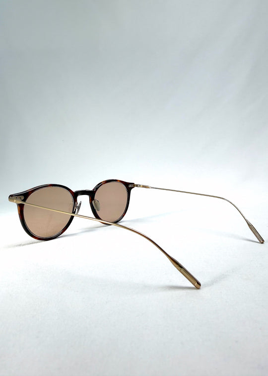 Side-temple view of Lunor Drift Softint sunglasses in Umber Fade showing curved titanium arms and translucent amber frame edges. 