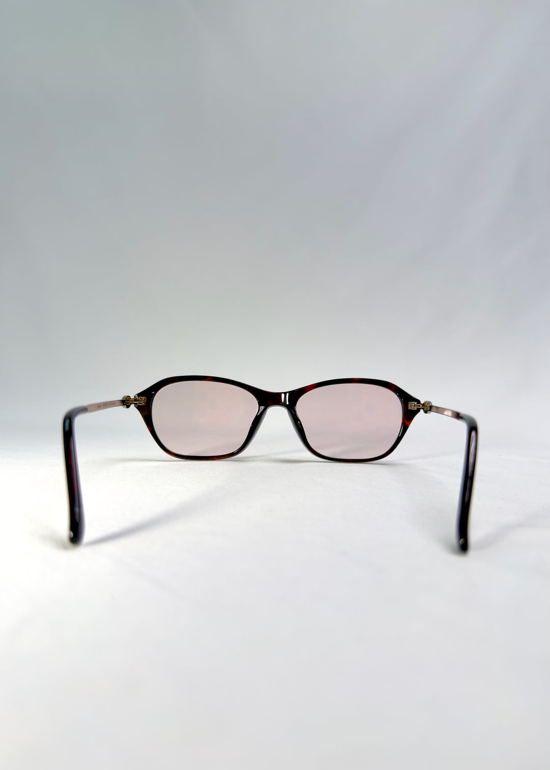 Back-angle view of Ravynor Softint sunglasses in Burnt Amber showing silver-metal temples and warm amber frame.