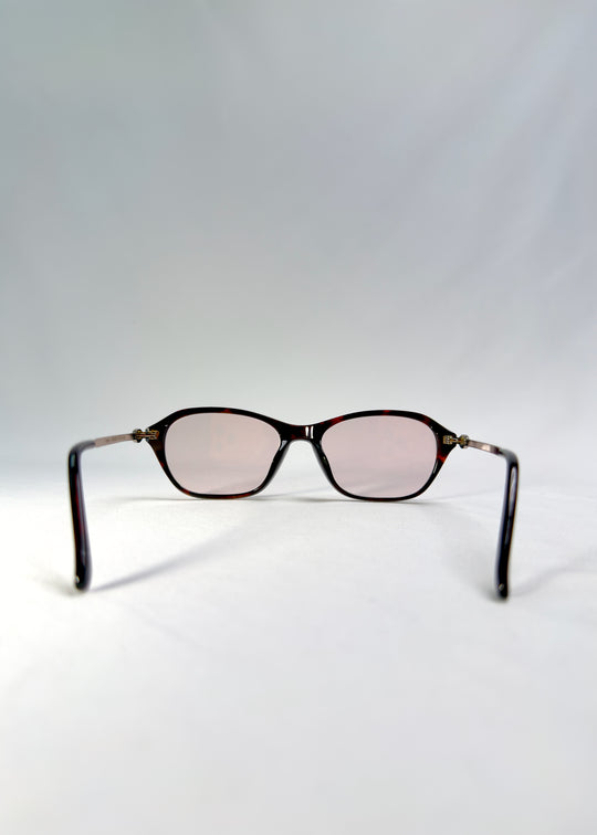 Back-angle view of Ravynor Softint sunglasses in Burnt Amber showing silver-metal temples and warm amber frame.