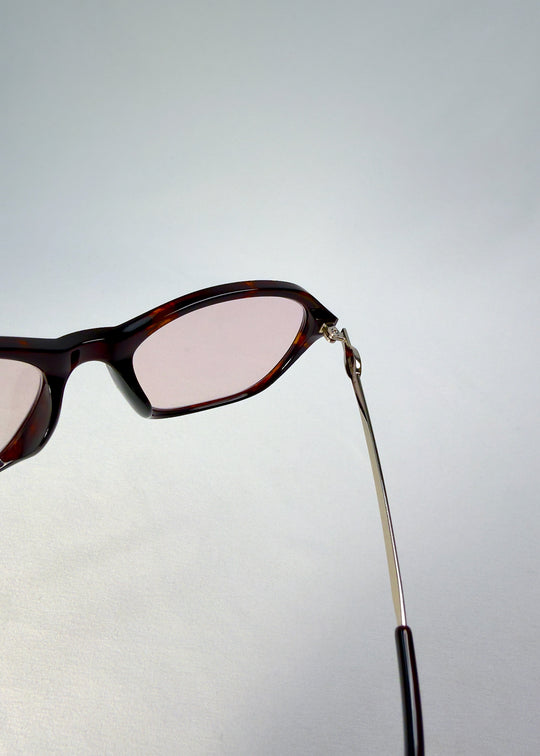 Close-up of Ravynor Softint sunglasses in Burnt Amber showing silver-metal hinge and acetate frame detail.