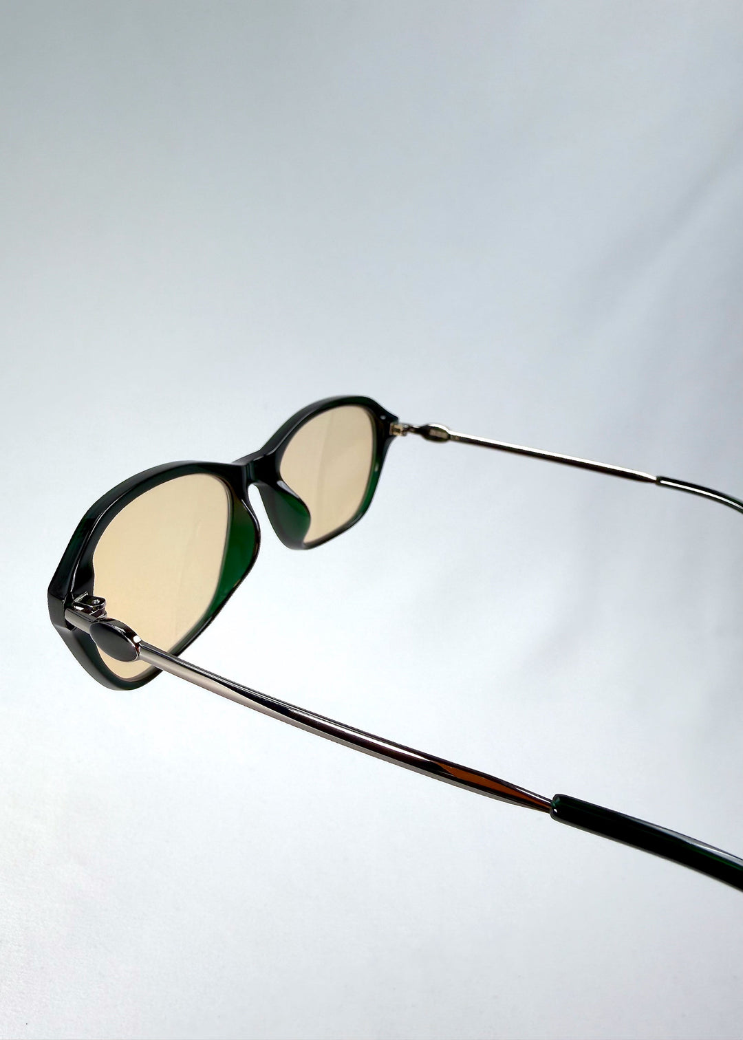 Back-angle view of Ravynor Softint sunglasses in Jade Shadow displaying slim stainless-steel temples and champagne-tinted lenses. 
