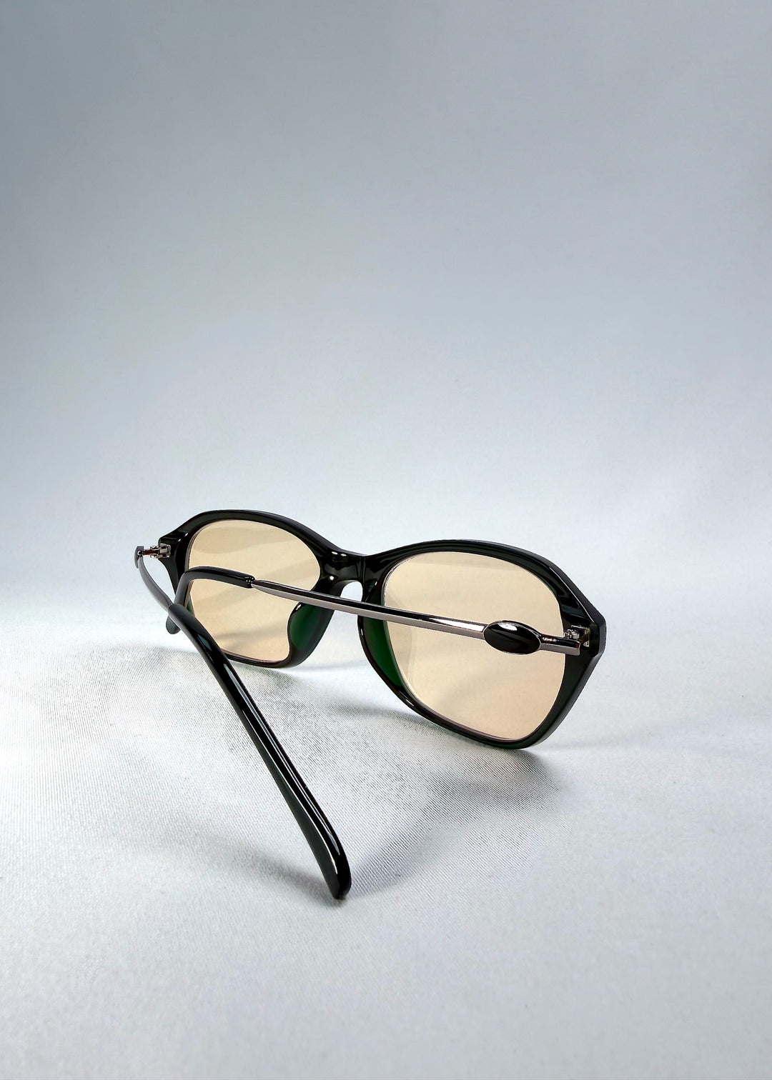 Folded-angle view of Ravynor Softint sunglasses in Jade Phase showing hybrid acetate-metal structure and lens tint.