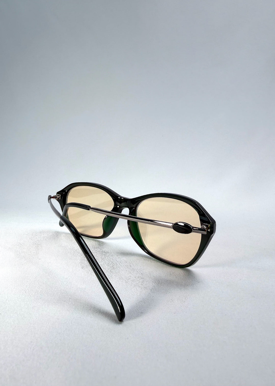 Folded-angle view of Ravynor Softint sunglasses in Jade Shadow showing the hybrid acetate and stainless-steel structure. 