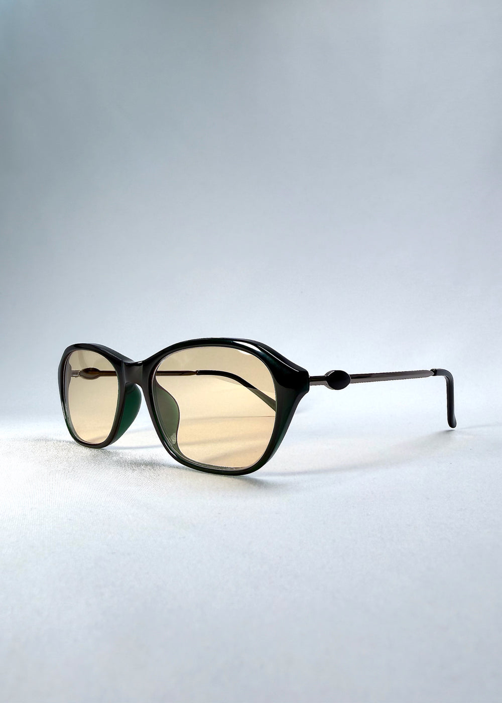 Folded-angle view of Ravynor Softint sunglasses in Jade Phase showing hybrid acetate-metal structure and lens tint.
