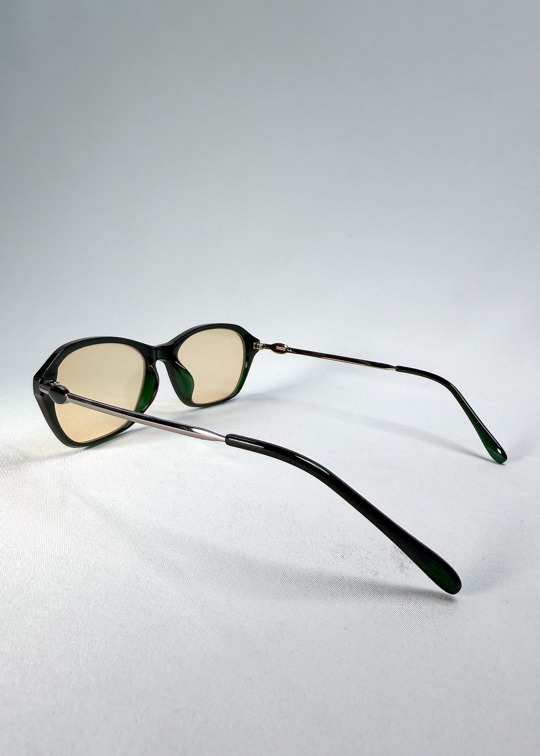 Side-temple view of Ravynor Softint sunglasses in Jade Shadow showing stainless-steel temples and deep green frame curvature. 
