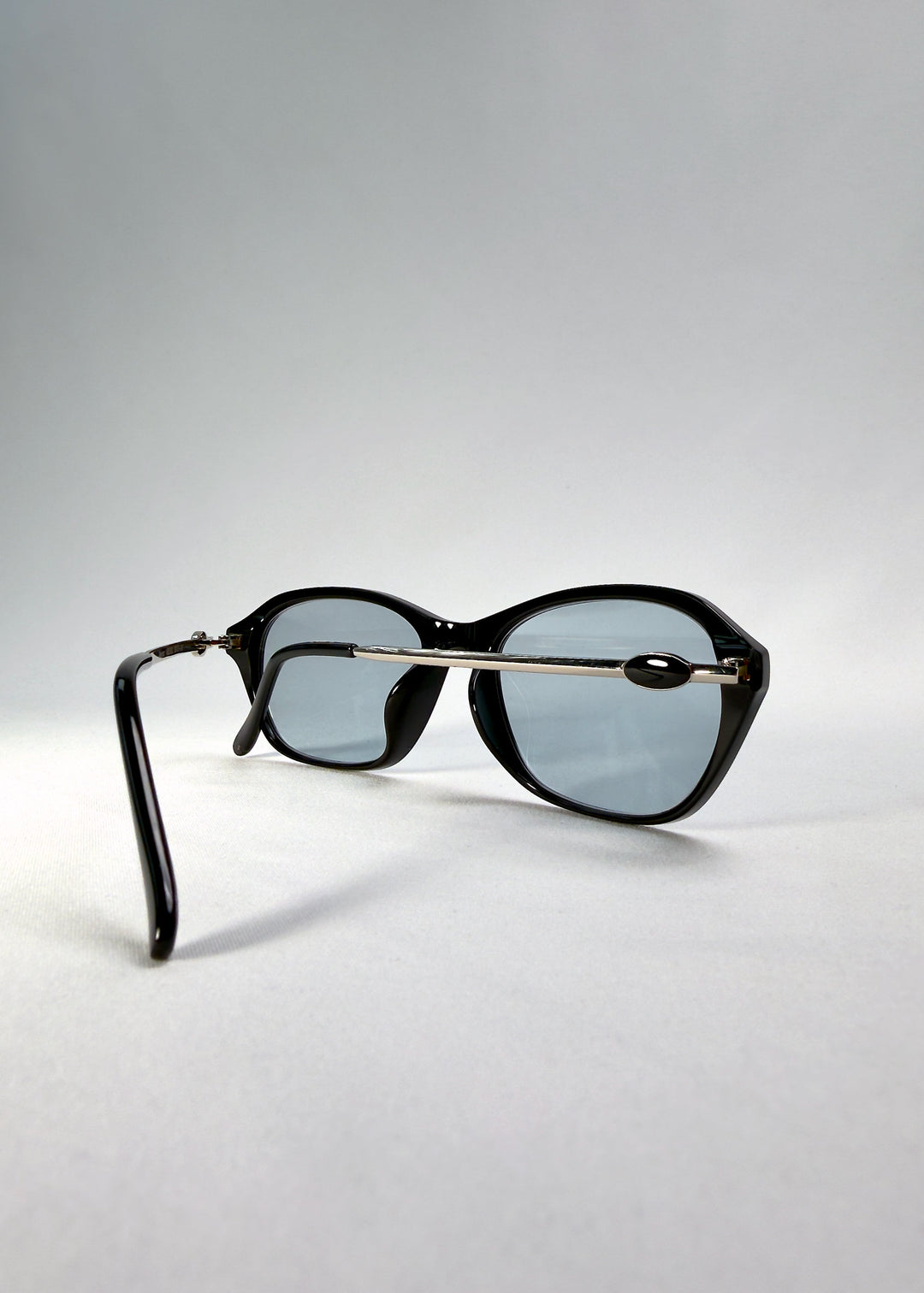 Folded-angle view of Ravynor Softint sunglasses in Noir Alloy displaying lightweight hybrid build and metal connection details. 
