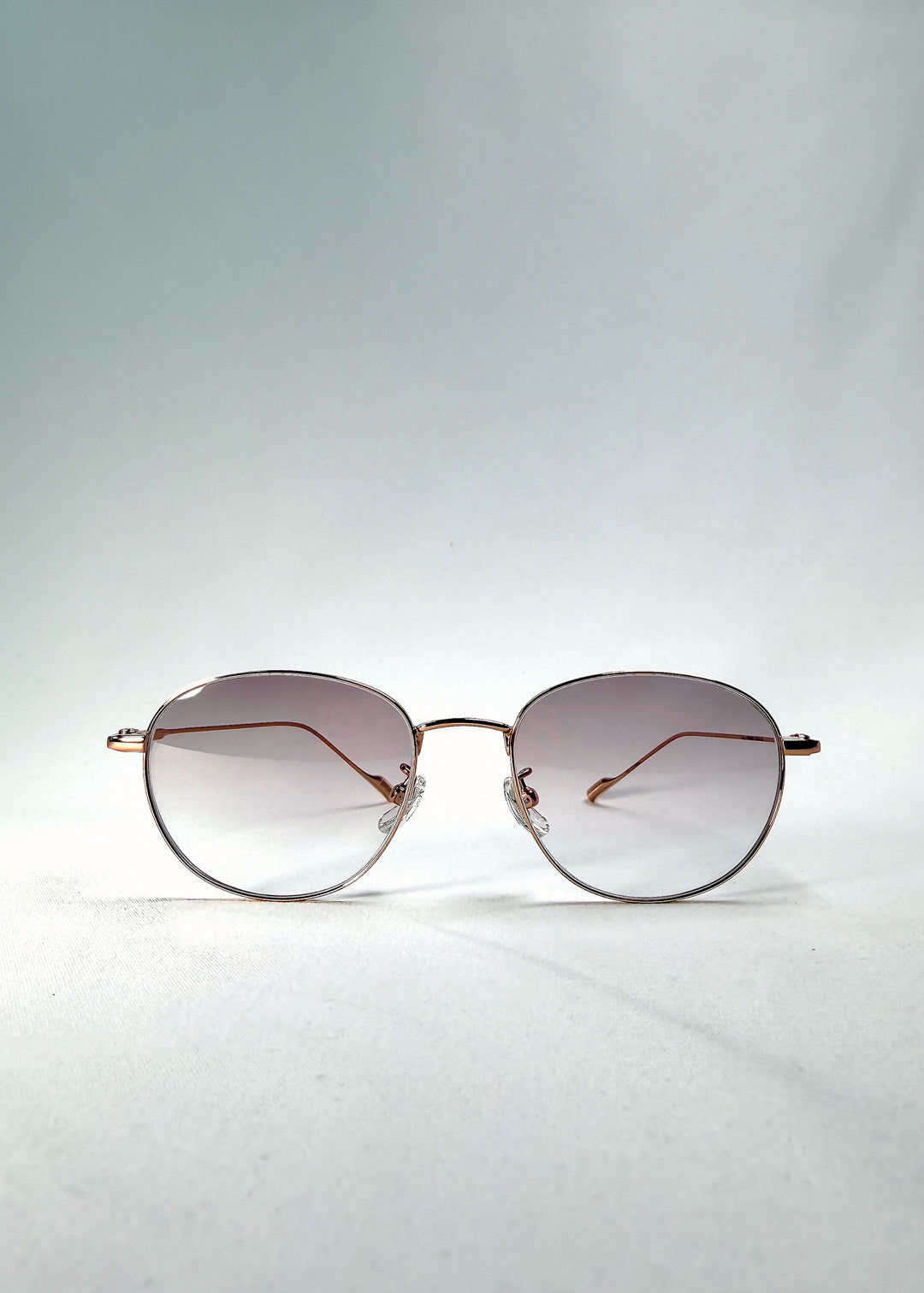 Front view of Solen Softint sunglasses in Dawnveil with round gold frame and lilac-grey Softint lenses.