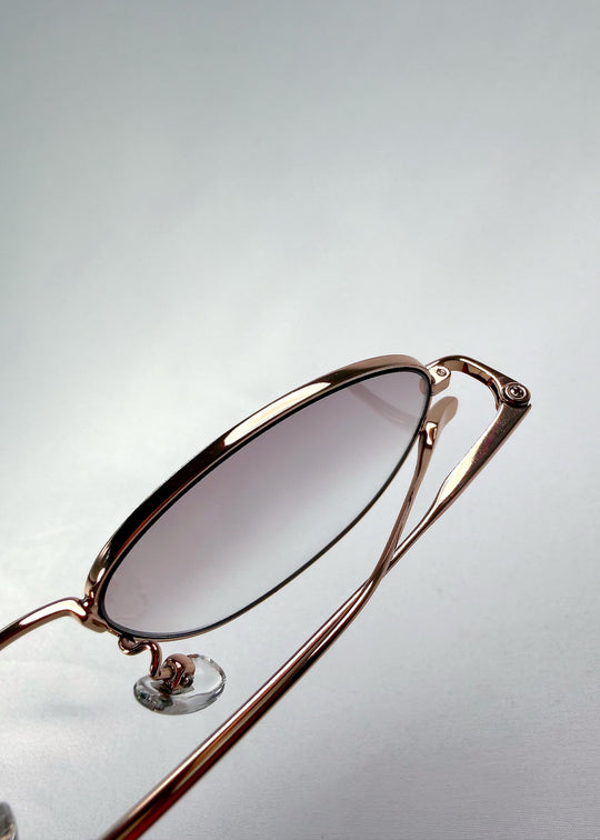Close-up of the hinge on Solen Softint sunglasses in Dawnveil, showing the gold frame and titanium temple connection. 