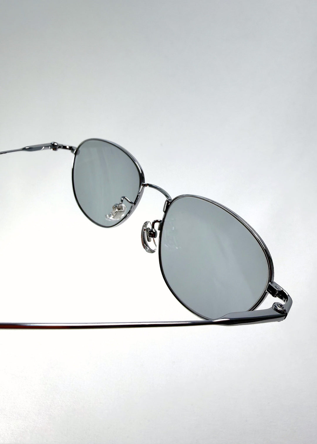 Close-up of the hinge on Solen Softint sunglasses in Moonveil, showing the silver frame and titanium temple connection. 