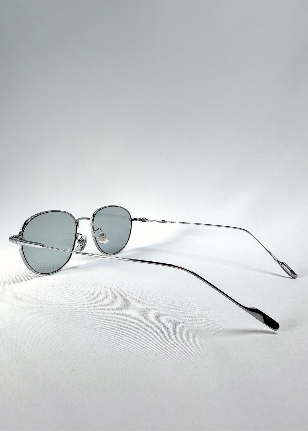 Three-quarter view of Solen Softint sunglasses in Moonveil, showing the reflective silver frame and pale blue-grey lenses. 