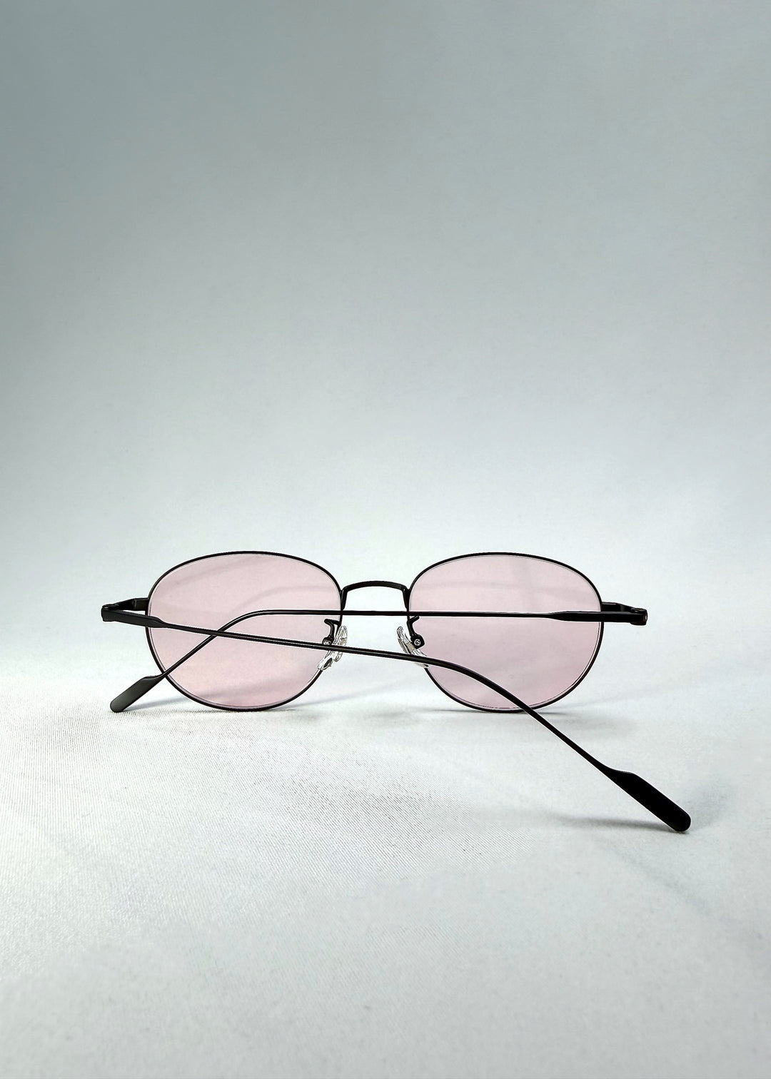 Folded-front view of Solen Softint sunglasses in Nightveil highlighting slender metal frame and soft pink tint.