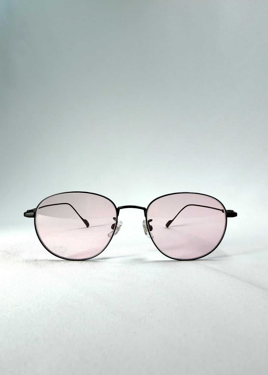 Front view of Solen Softint sunglasses in Nightveil showing matte black frame and pale rose lenses.