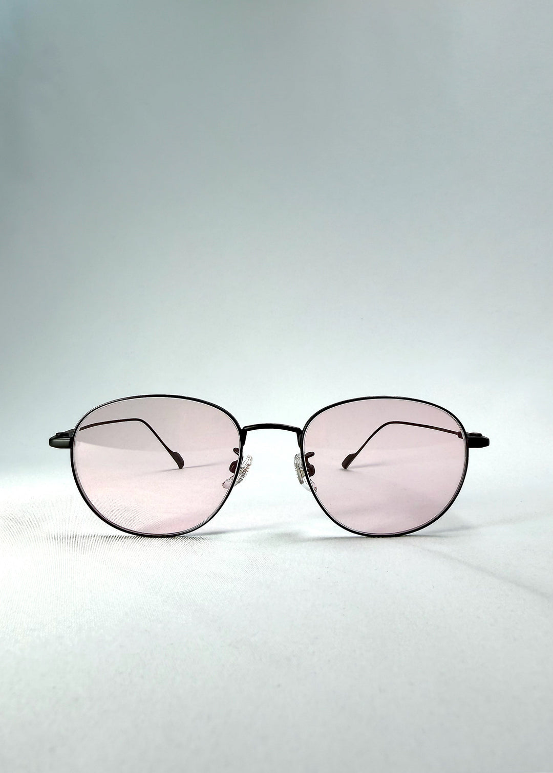 Front view of Solen Softint sunglasses in Nightveil, showing the matte black stainless-steel frame and pale rose lenses. 
