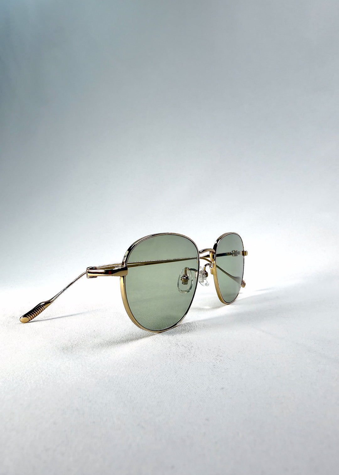 Three-quarter front view of Solen Softint sunglasses in Sunveil, highlighting the gold frame and pale green lenses. 