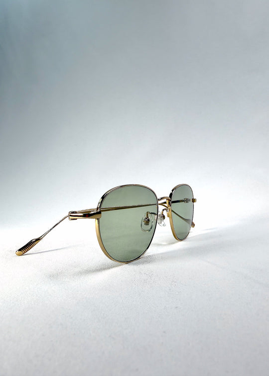 Three-quarter front view of Solen Softint sunglasses in Sunveil, highlighting the gold frame and pale green lenses. 