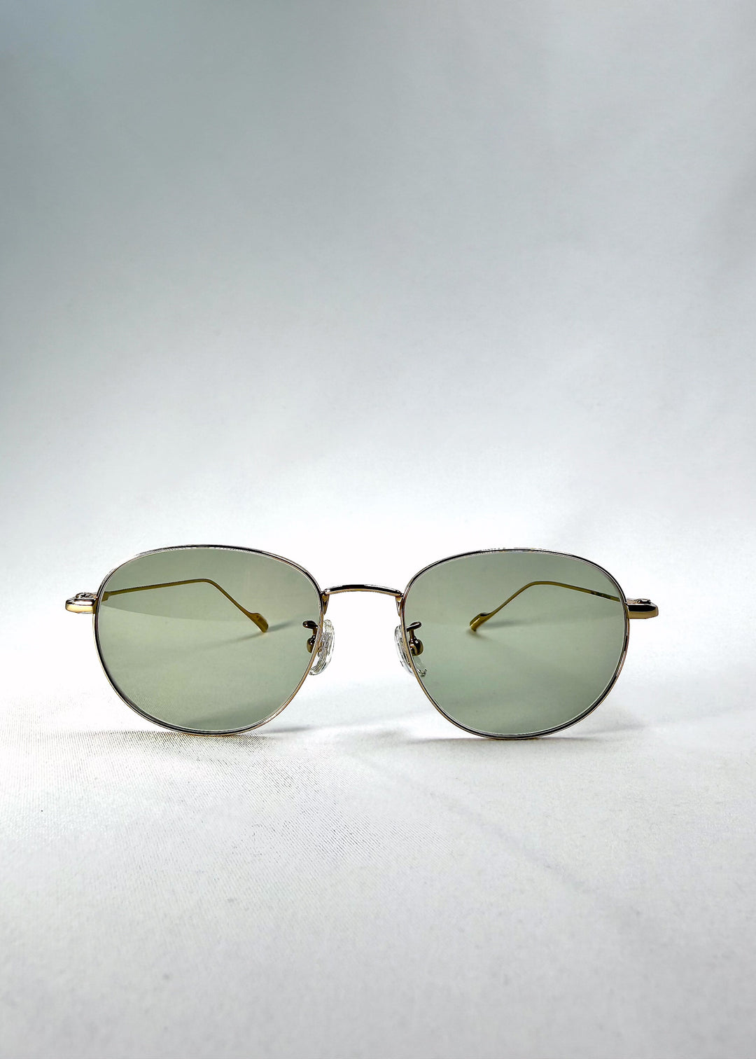 Front view of Solen Softint sunglasses in Sunveil, showing the gold stainless-steel frame and pale green lenses. 