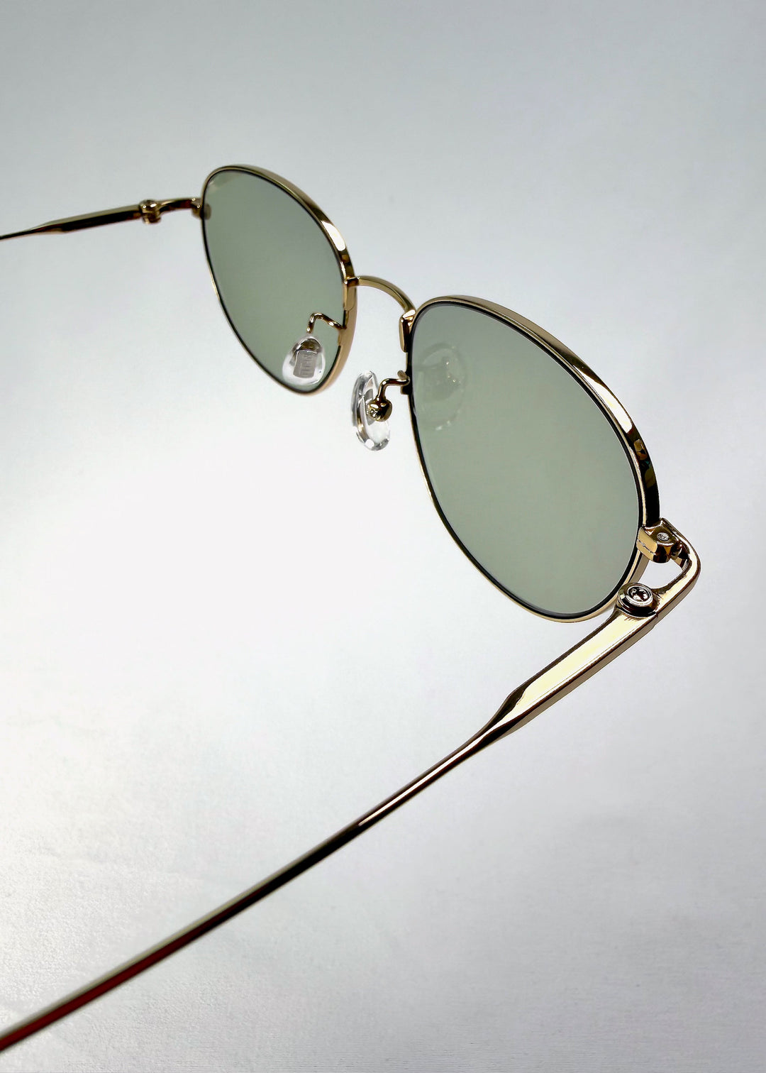 Close-up of the hinge on Solen Softint sunglasses in Sunveil, showing the gold frame and titanium temple connection. 