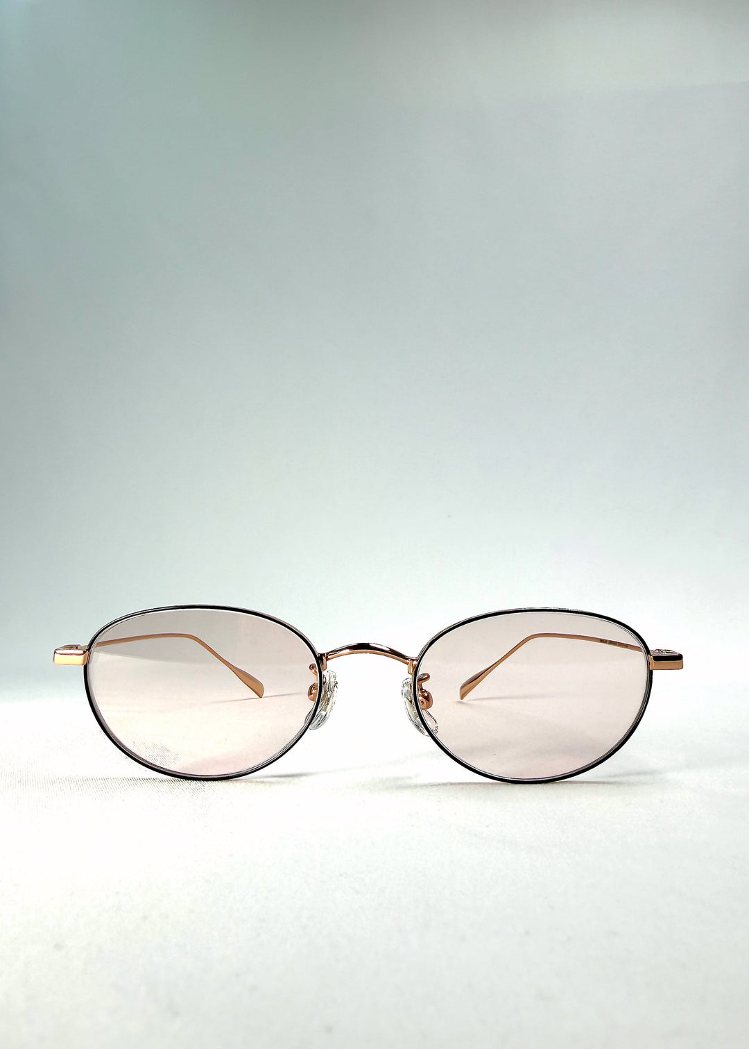 Front view of Vanta Arc Softint sunglasses in Champagne Gold showing the gold oval frame and pale rose-beige lenses. 