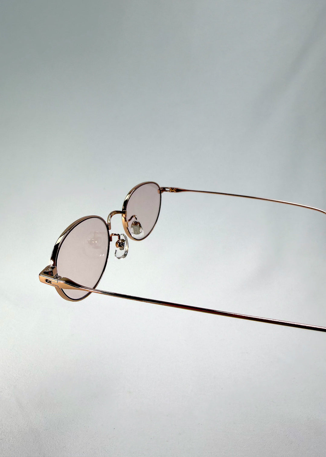 Close-up of Vanta Arc Softint sunglasses in Champagne Gold highlighting the hinge detail and rose-beige lens tint. 