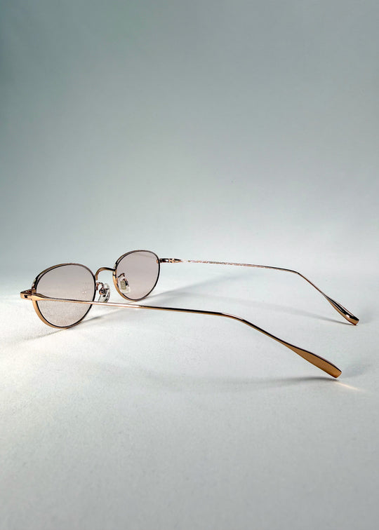 Side-temple view of Vanta Arc Softint sunglasses in Duskgold showing titanium arms and sleek oval silhouette.