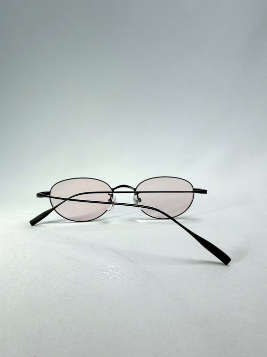 Folded-back view of Vanta Arc Softint sunglasses in Blush Noir showing the matte black frame and pale blush lenses. 