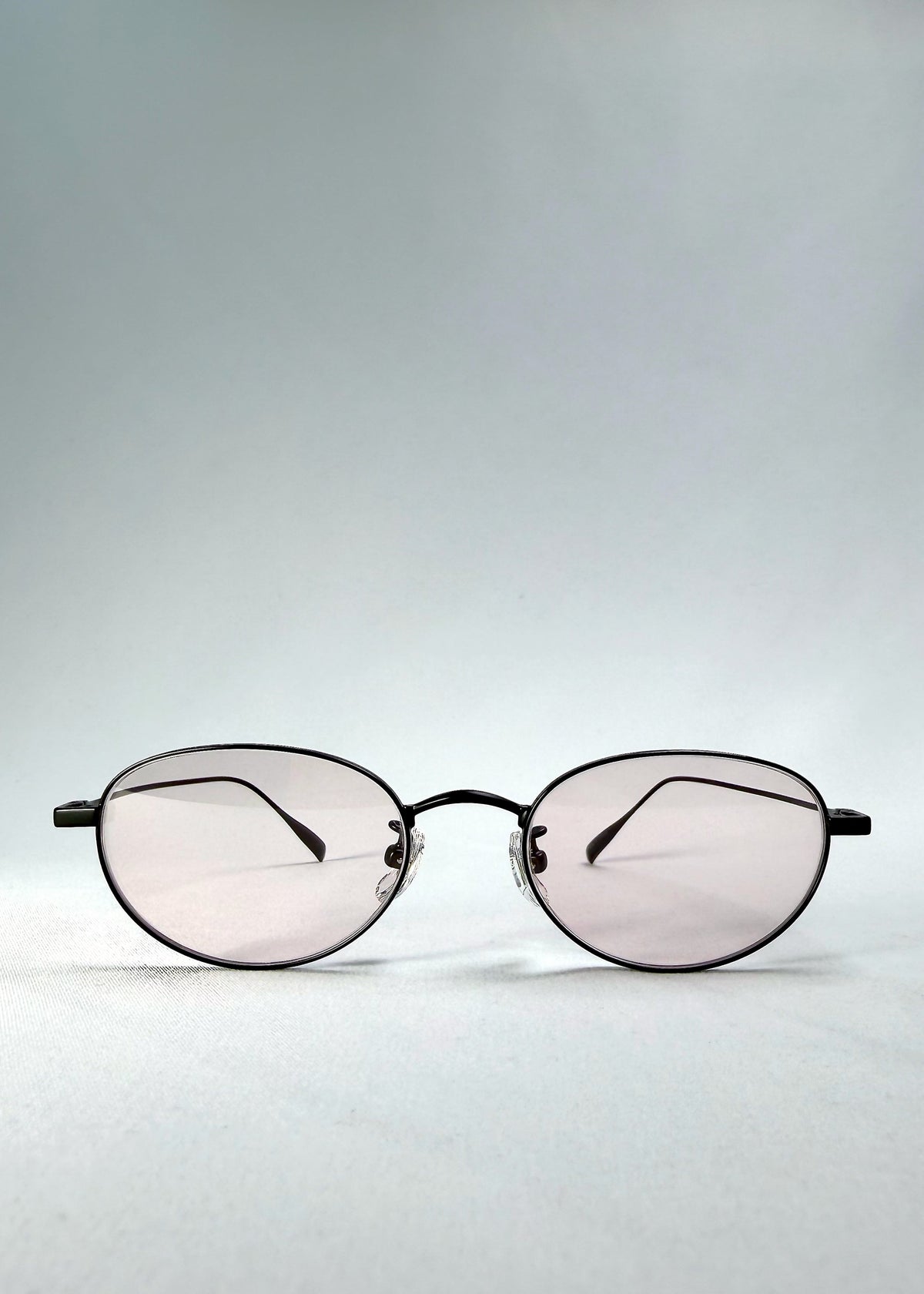 Front view of Vanta Arc Softint sunglasses in Blush Noir showing the black oval frame and pale blush lenses.