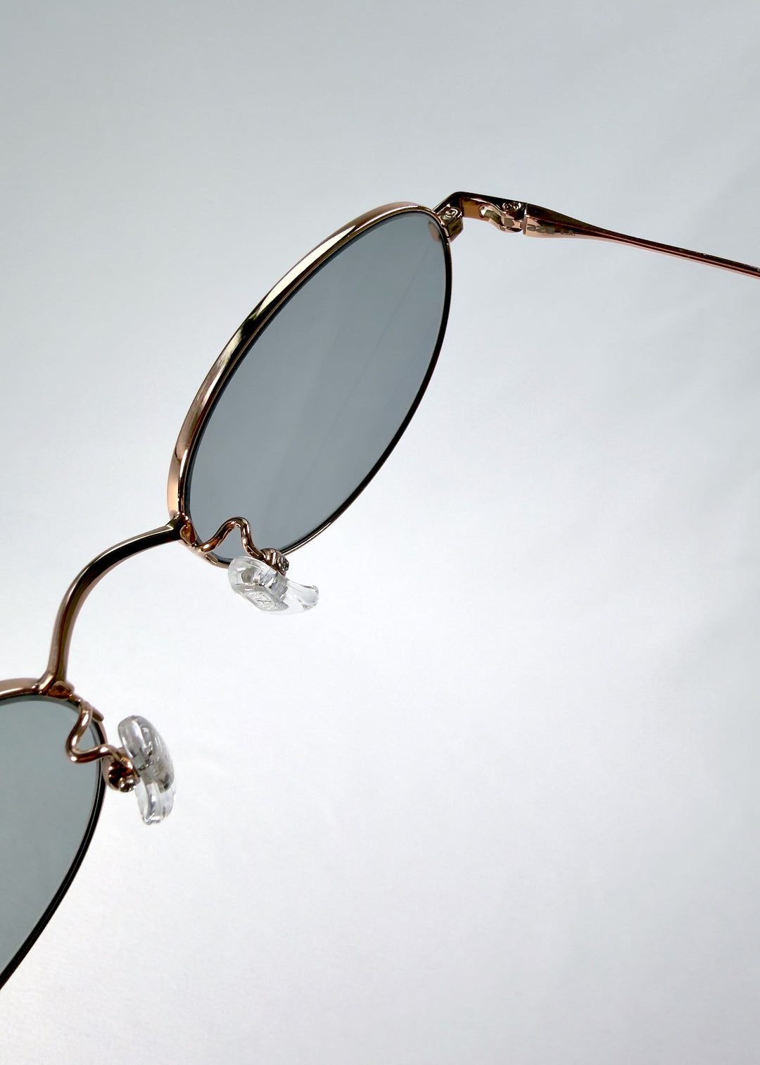 Close-up of Vanta Arc Softint sunglasses in Sage Rose highlighting the lens edge and polished hinge detail. 