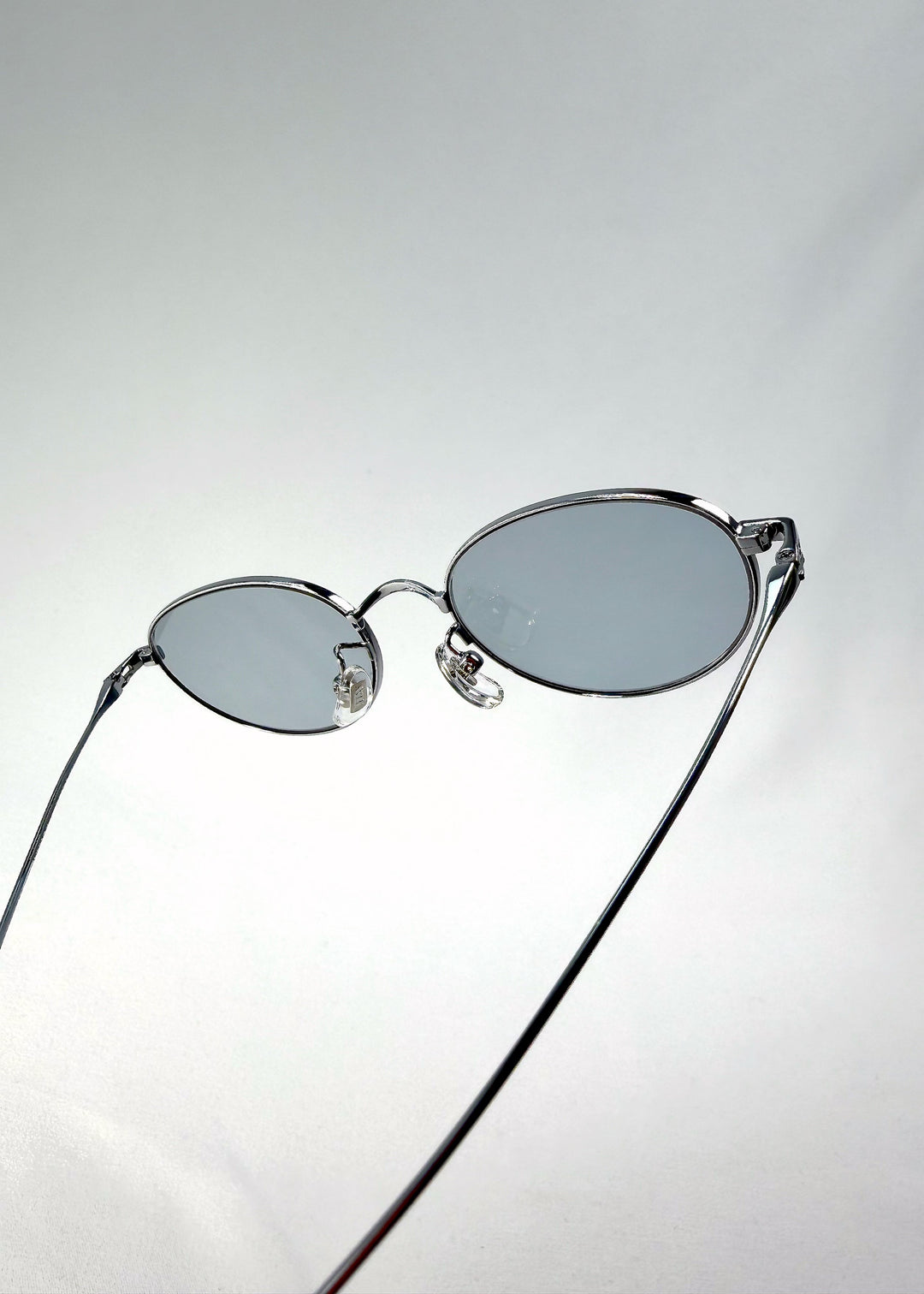 Close-up of Vanta Arc Softint sunglasses in Glacial Silver highlighting the hinge and grey-blue lens edge. 