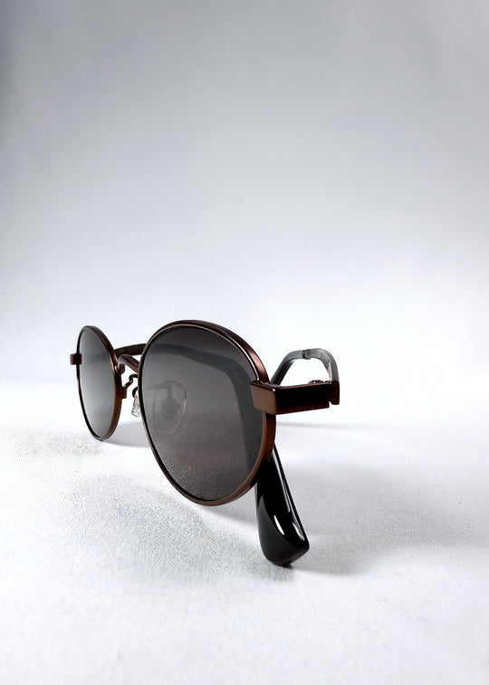 Folded frame view of Solstice – Espresso Bronze sunglasses displaying the oval lens shape and flexible temple design. 