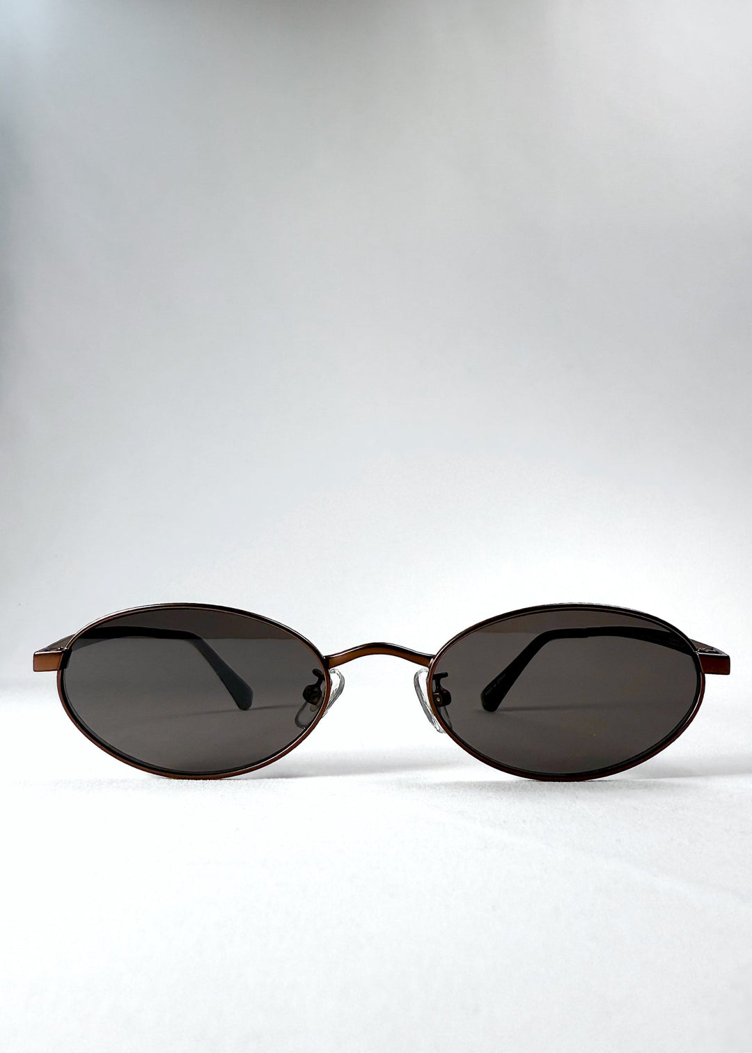 Front view of Solstice – Espresso Bronze sunglasses showing the espresso-toned oval frame and smoky brown lenses. 
