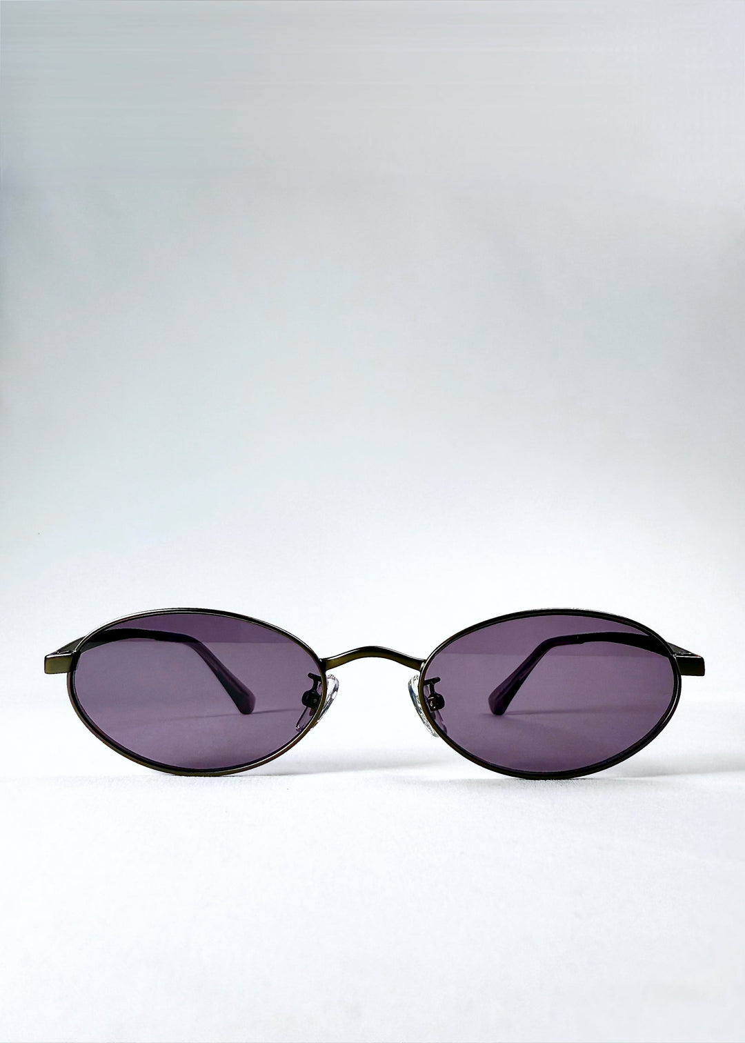 Front view of Solstice – Gunmetal Frost sunglasses showing the oval frame and purple lenses. 