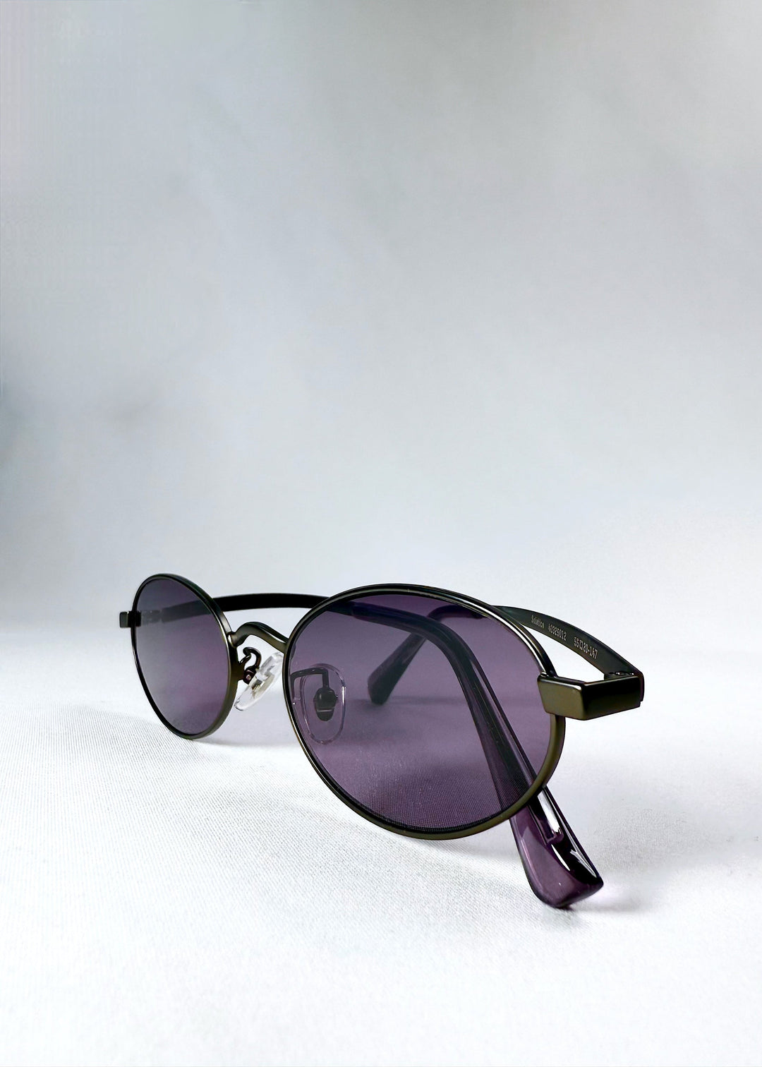 Close-up of Solstice – Gunmetal Frost sunglasses showing the gunmetal hinge and frame detail, highlighting the vibrant purple lens and acetate arm design. 