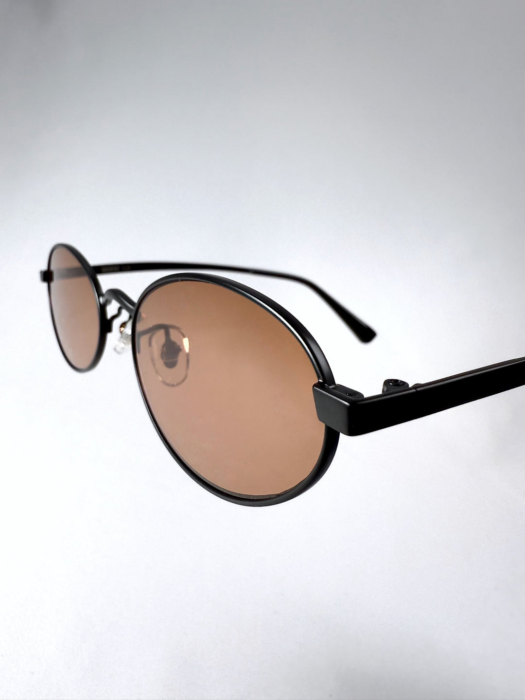Close-up of Solstice – Mahogany Black sunglasses front frame with brown lens detailing and bold minimalist style.
