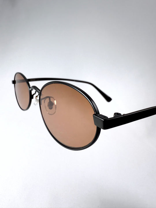 Close-up of Solstice – Mahogany Black sunglasses front frame with brown lens detailing and bold minimalist style.