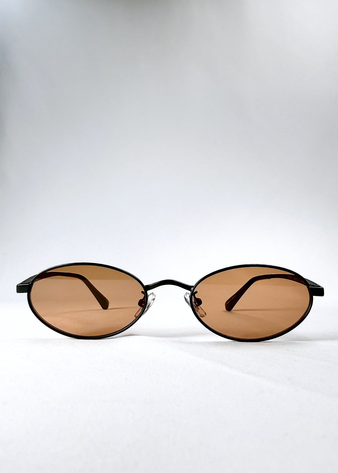 Front view of Solstice sunglasses in Mahogany Black showing the full oval frame and warm brown lenses. 