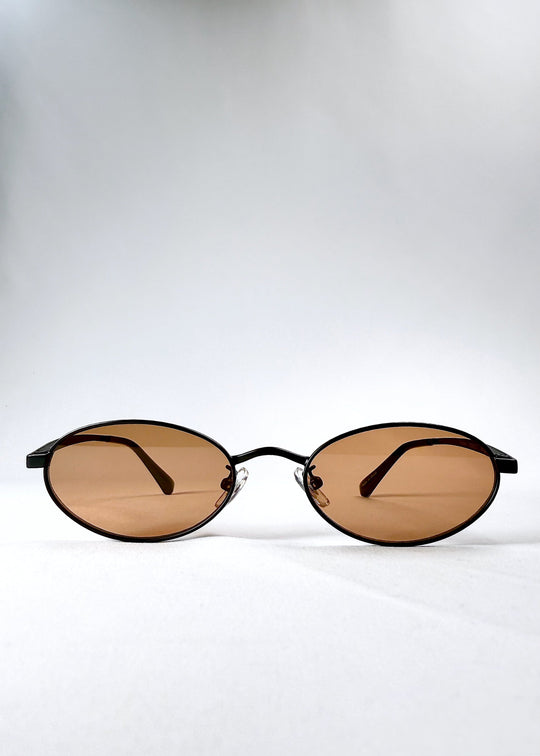 Front view of Solstice sunglasses in Mahogany Black showing the full oval frame and warm brown lenses. 