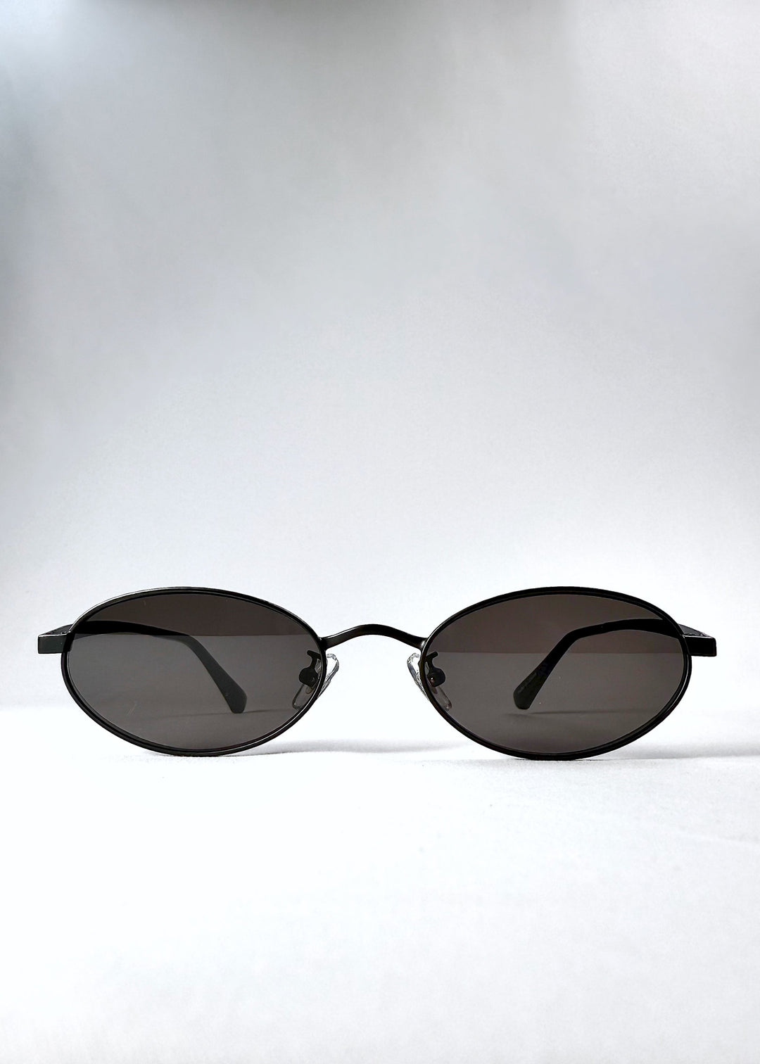 Front view of Solstice – Shadow Black sunglasses, showcasing the compact oval lenses and deep grey tint.
