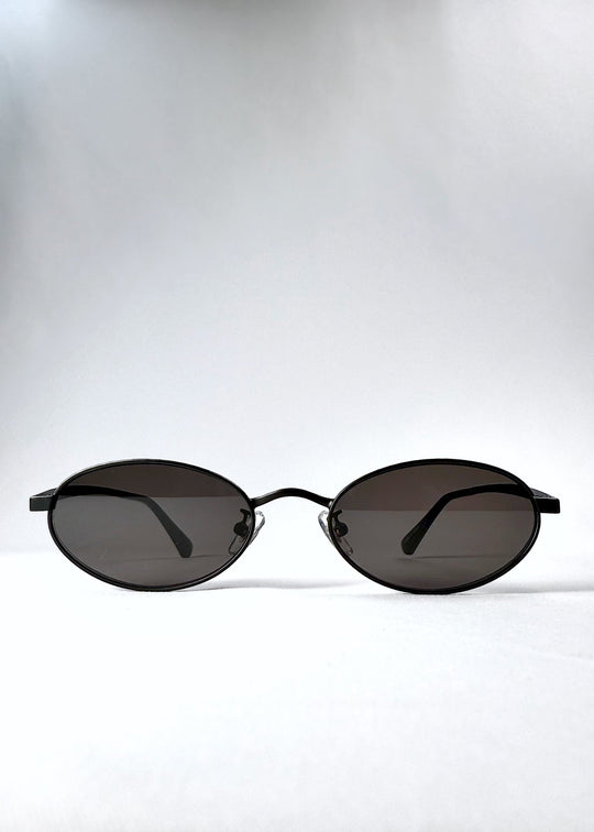 Front view of Solstice – Shadow Black sunglasses, showcasing the compact oval lenses and deep grey tint. 