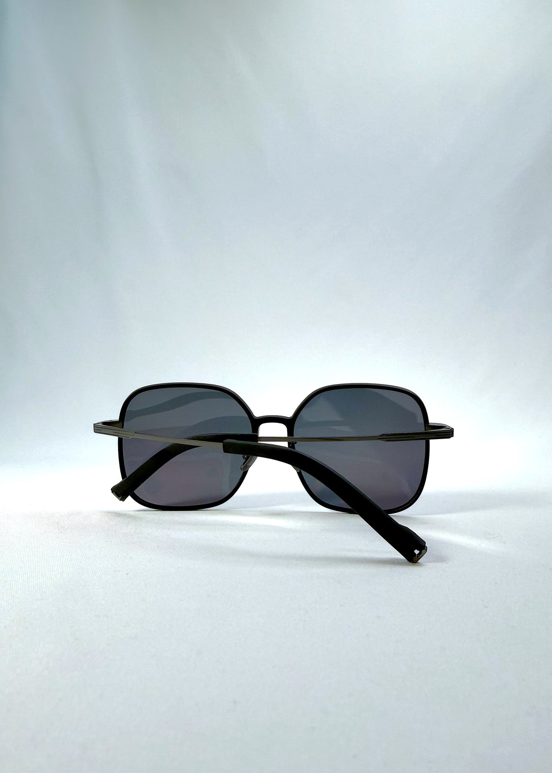 Folded view of Spica sunglasses in Black, featuring an ultra-light frame with titanium temples and polarized lenses, showing the folded temples and frame profile. 
