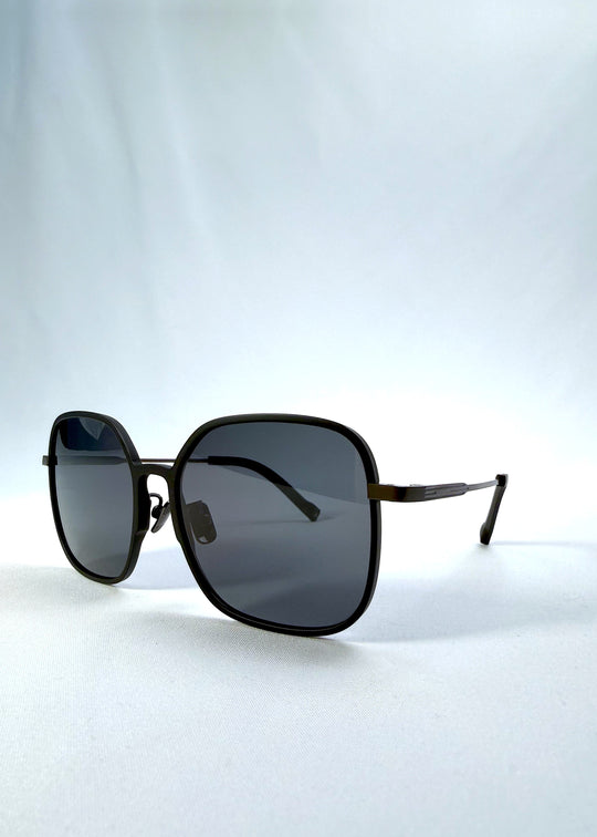 Three-quarter front view of Spica sunglasses in Black, featuring an ultra-light frame with titanium temples and polarized lenses, showing the front shape and temple profile. 