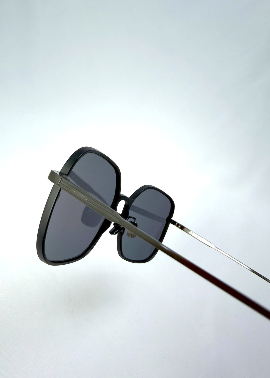 Close-up temple detail view of Spica sunglasses in Black, featuring an ultra-light frame with titanium temples and polarized lenses, showing the temple arm and hinge area. 